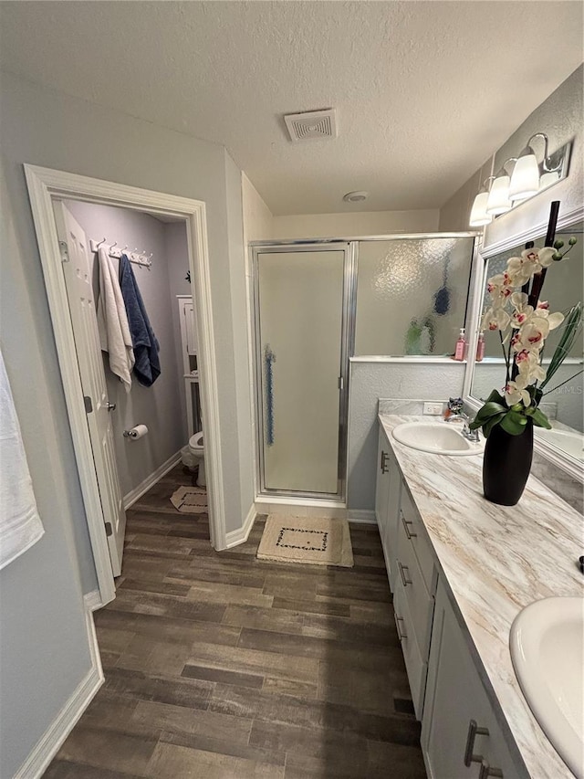 5547 SE 91st Pl, Ocala, FL 34480 - full bathroom featuring wood finished floors, a shower stall, double vanity, toilet, and a textured ceiling