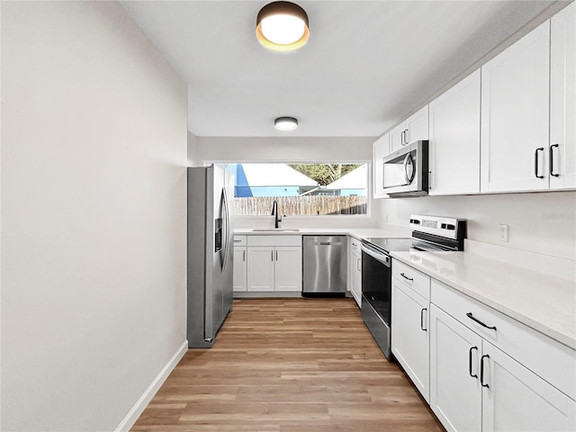 5136 Cedar Hammock Dr, Sarasota, FL 34232 - kitchen featuring stainless steel appliances, white cabinetry, a sink, light wood-style floors, and light countertops