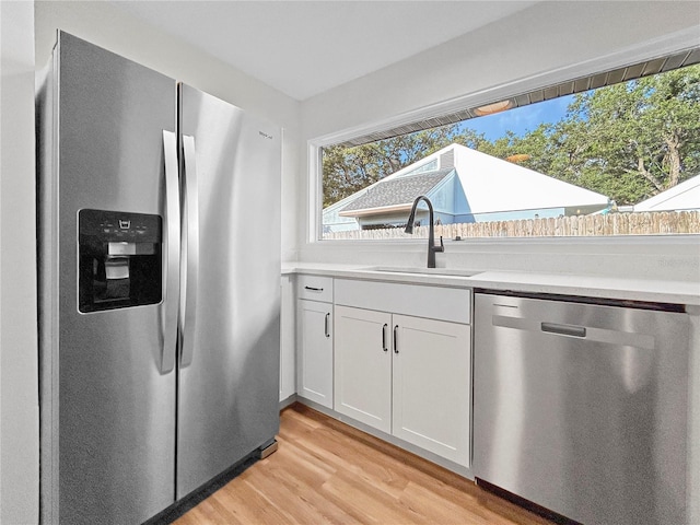 5136 Cedar Hammock Dr, Sarasota, FL 34232 - kitchen featuring stainless steel appliances, a sink, light wood finished floors, white cabinets, and light countertops