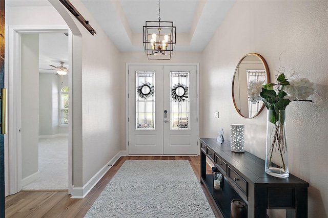 440 Bellissimo Pl, Howey In The Hills, FL 34737 - foyer featuring wood finished floors, a raised ceiling, french doors, a chandelier, and baseboards