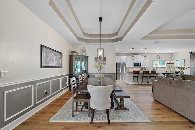 440 Bellissimo Pl, Howey In The Hills, FL 34737 - dining room with a tray ceiling, light wood-type flooring, a wainscoted wall, recessed lighting, and a chandelier