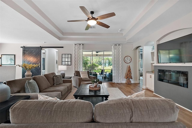 440 Bellissimo Pl, Howey In The Hills, FL 34737 - living area featuring a tray ceiling, arched walkways, ceiling fan, and wood finished floors