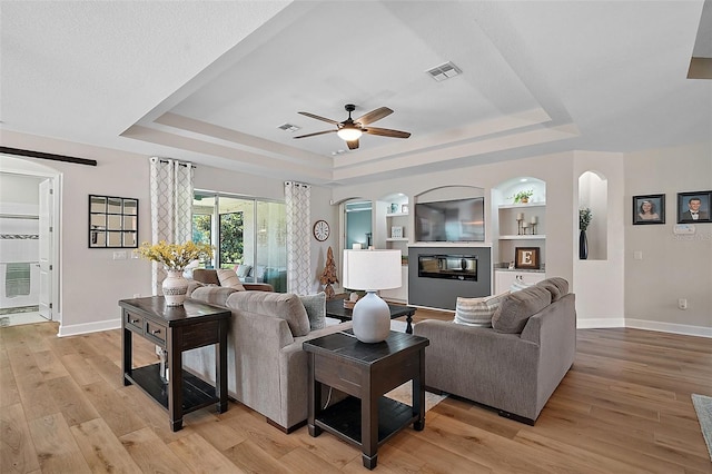 440 Bellissimo Pl, Howey In The Hills, FL 34737 - living room featuring a raised ceiling, arched walkways, and baseboards
