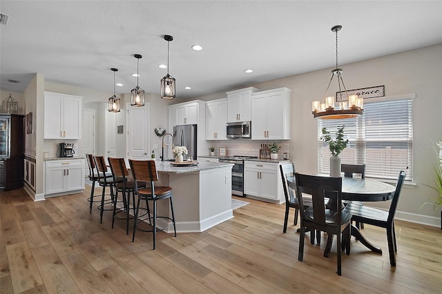 440 Bellissimo Pl, Howey In The Hills, FL 34737 - kitchen with stainless steel appliances, a chandelier, decorative backsplash, light wood finished floors, and recessed lighting