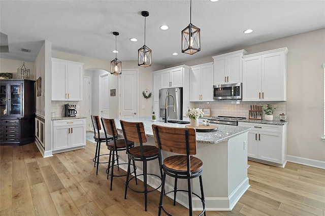 440 Bellissimo Pl, Howey In The Hills, FL 34737 - kitchen featuring stainless steel appliances, a sink, light wood finished floors, recessed lighting, and arched walkways