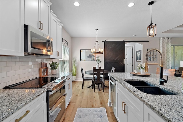 440 Bellissimo Pl, Howey In The Hills, FL 34737 - kitchen with appliances with stainless steel finishes, a sink, light wood-style flooring, backsplash, and white cabinets