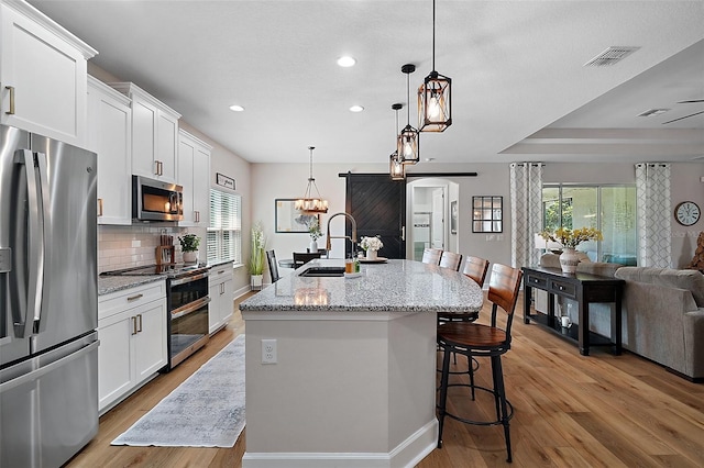 440 Bellissimo Pl, Howey In The Hills, FL 34737 - kitchen with stainless steel appliances, recessed lighting, open floor plan, a kitchen breakfast bar, and light wood finished floors