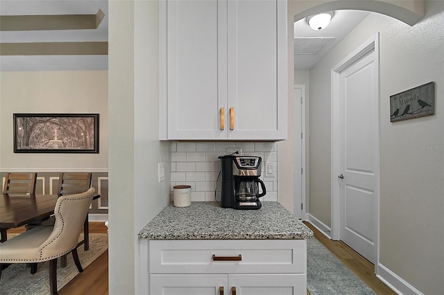 440 Bellissimo Pl, Howey In The Hills, FL 34737 - kitchen featuring dark wood finished floors, white cabinetry, decorative backsplash, baseboards, and light stone countertops