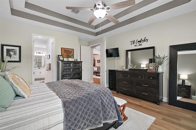 440 Bellissimo Pl, Howey In The Hills, FL 34737 - bedroom with light wood-type flooring, a tray ceiling, baseboards, connected bathroom, and a ceiling fan
