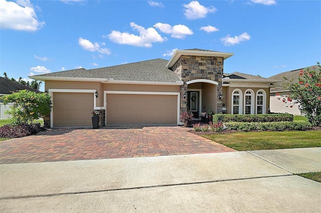 440 Bellissimo Pl, Howey In The Hills, FL 34737 - view of front of property featuring stucco siding, decorative driveway, a garage, stone siding, and a front lawn
