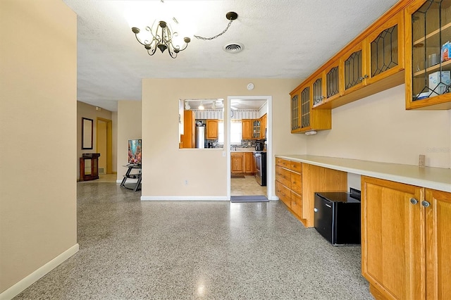 2007 Mosher Dr, Orlando, FL 32810 - kitchen featuring brown cabinetry, baseboards, and a textured ceiling