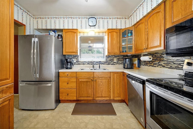 2007 Mosher Dr, Orlando, FL 32810 - kitchen featuring appliances with stainless steel finishes, a sink, brown cabinetry, light countertops, and tasteful backsplash