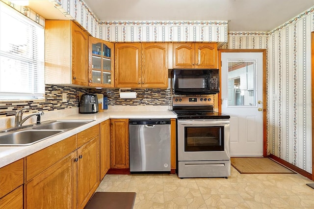 2007 Mosher Dr, Orlando, FL 32810 - kitchen featuring appliances with stainless steel finishes, a sink, wallpapered walls, brown cabinets, and light countertops