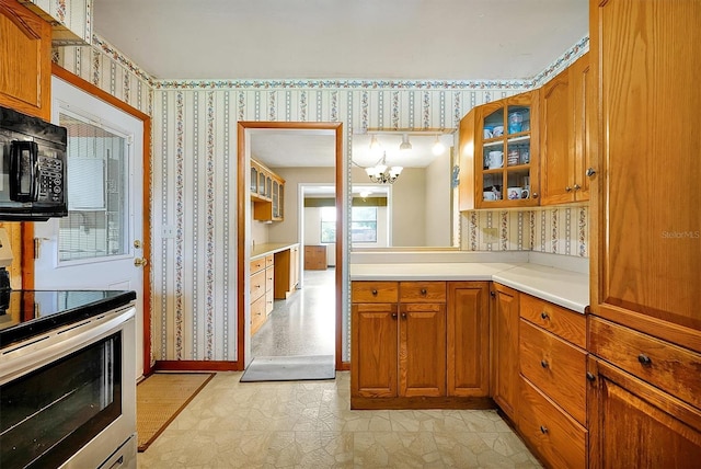 2007 Mosher Dr, Orlando, FL 32810 - kitchen with stainless steel range with electric stovetop, wallpapered walls, brown cabinets, black microwave, and a chandelier
