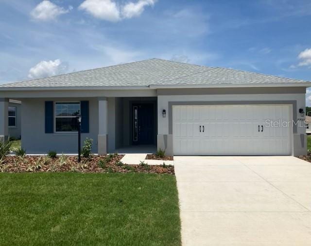8855 SW 72nd Loop, Ocala, FL 34481 - single story home with stucco siding, an attached garage, a front lawn, concrete driveway, and a shingled roof