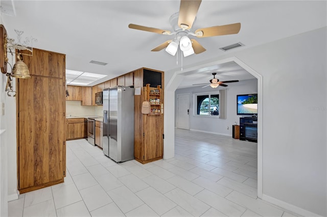 6443 34th Ave N, Saint Petersburg, FL 33710 - kitchen featuring stainless steel appliances, ceiling fan, brown cabinetry, light countertops, and baseboards