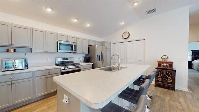 3817 Miragalia Ln, The Villages, FL 32163 - kitchen with stainless steel appliances, a sink, gray cabinets, lofted ceiling, and a kitchen island with sink