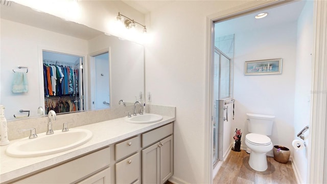3817 Miragalia Ln, The Villages, FL 32163 - bathroom featuring a shower stall, a walk in closet, double vanity, toilet, and wood finished floors