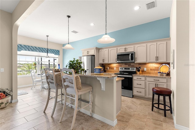 11215 SE 172nd Pl, Summerfield, FL 34491 - kitchen featuring stainless steel appliances, backsplash, a kitchen breakfast bar, light stone countertops, and a center island