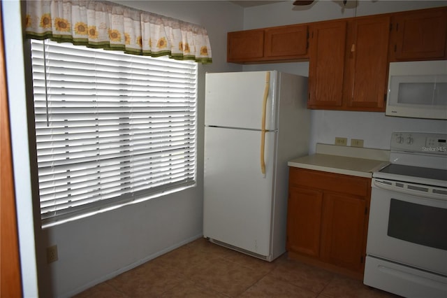 610 Swallow Ct, Apopka, FL 32712 - kitchen with white appliances, light countertops, brown cabinets, light tile patterned floors, and baseboards