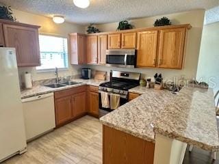 3337 Candlebrook St, The Villages, FL 32162 - kitchen featuring stainless steel appliances, a peninsula, a sink, a textured ceiling, and light stone countertops