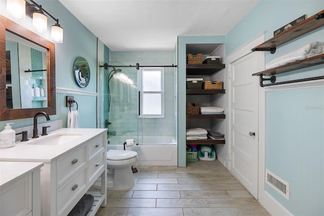 378 W Osceola St, Clermont, FL 34711 - bathroom featuring vanity, toilet, shower / bath combination with glass door, wainscoting, and wood finished floors