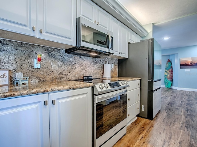 3425 S Atlantic Ave Unit 1101, Daytona Beach, FL 32118 - kitchen with appliances with stainless steel finishes, light wood-style flooring, decorative backsplash, white cabinets, and light stone counters