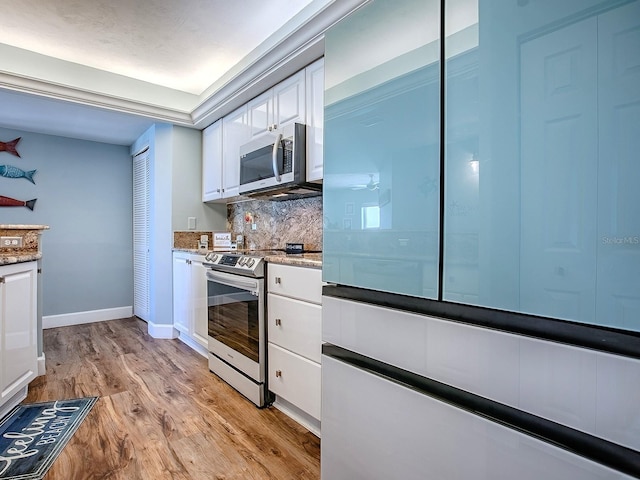 3425 S Atlantic Ave Unit 1101, Daytona Beach, FL 32118 - kitchen featuring appliances with stainless steel finishes, white cabinets, decorative backsplash, light wood-style flooring, and baseboards