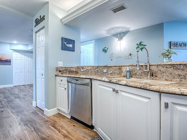 3425 S Atlantic Ave Unit 1101, Daytona Beach, FL 32118 - kitchen featuring stainless steel dishwasher, a sink, light wood-style floors, white cabinets, and light stone countertops