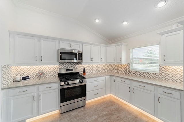 3769 Causey Ct, The Villages, FL 32163 - kitchen with stainless steel appliances, lofted ceiling, light countertops, white cabinets, and ornamental molding