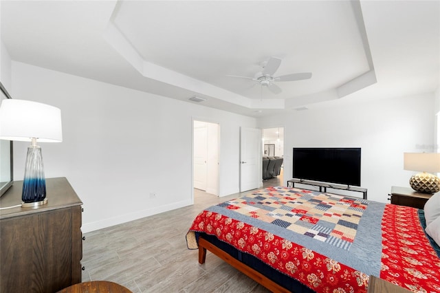 3769 Causey Ct, The Villages, FL 32163 - bedroom with a tray ceiling, baseboards, light wood-style flooring, and a ceiling fan