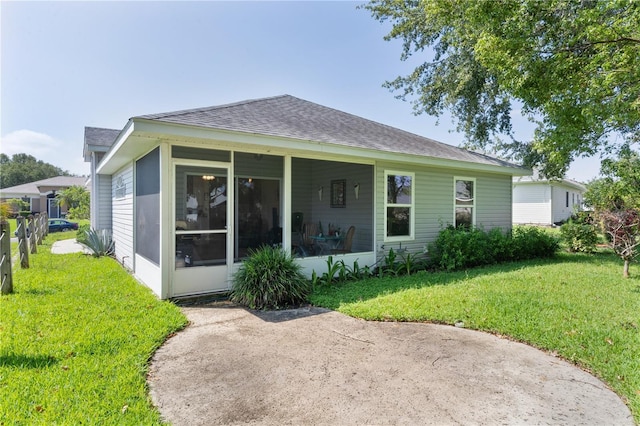 2821 Mediterranean Loop, Tavares, FL 32778 - rear view of house featuring a sunroom, a shingled roof, and a lawn