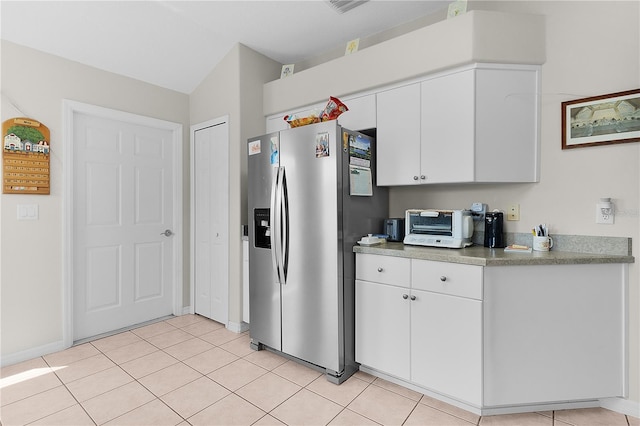 2821 Mediterranean Loop, Tavares, FL 32778 - kitchen with stainless steel refrigerator with ice dispenser, white cabinets, light tile patterned floors, and baseboards