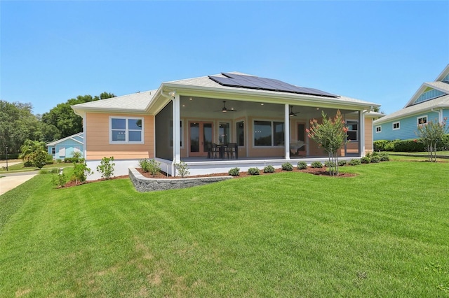 1127 Fiesta Key Cir, Lady Lake, FL 32159 - back of property with a ceiling fan, roof mounted solar panels, a lawn, and a sunroom