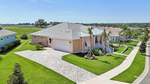 1127 Fiesta Key Cir, Lady Lake, FL 32159 - view of side of property with decorative driveway, a garage, a lawn, a shingled roof, and a residential view