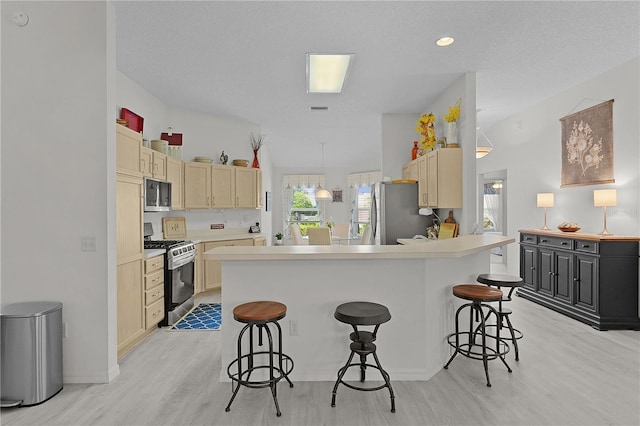 2738 Morven Park Way, The Villages, FL 32162 - kitchen featuring stainless steel appliances, light wood-style floors, a breakfast bar area, light countertops, and a peninsula