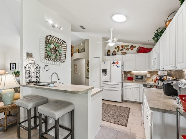 17380 SE 111th Ct, Summerfield, FL 34491 - kitchen featuring white appliances, a ceiling fan, a breakfast bar, vaulted ceiling, and white cabinets