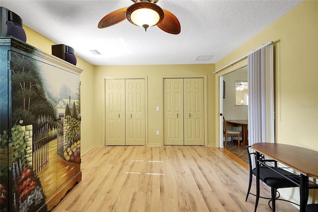2766 Privada Dr, The Villages, FL 32162 - bedroom featuring two closets, light wood-type flooring, a textured ceiling, a ceiling fan, and baseboards