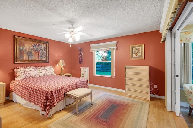 2766 Privada Dr, The Villages, FL 32162 - bedroom featuring light wood-style flooring, a textured ceiling, ceiling fan, and baseboards