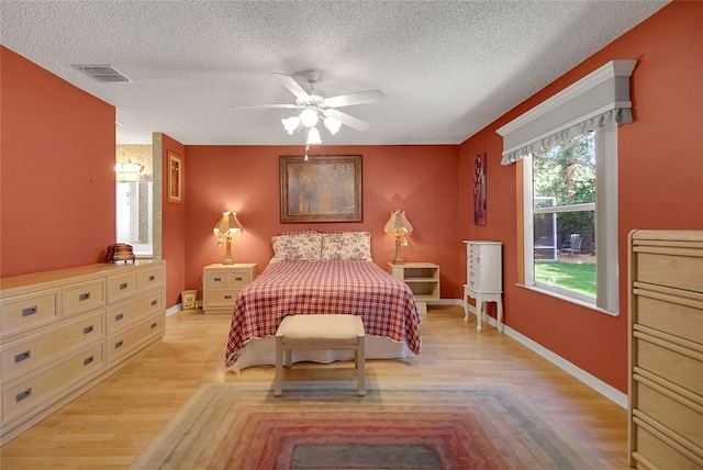 2766 Privada Dr, The Villages, FL 32162 - bedroom with light wood-type flooring, a textured ceiling, baseboards, and a ceiling fan