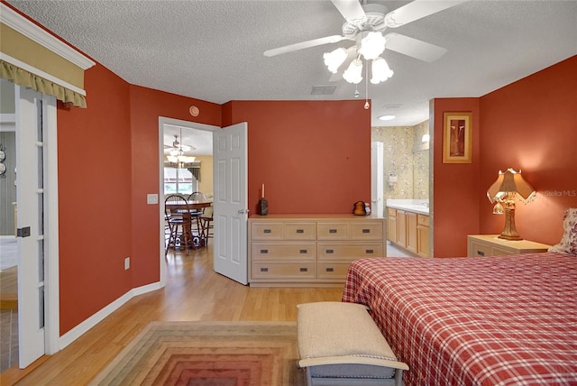 2766 Privada Dr, The Villages, FL 32162 - bedroom with light wood finished floors, a textured ceiling, baseboards, and connected bathroom