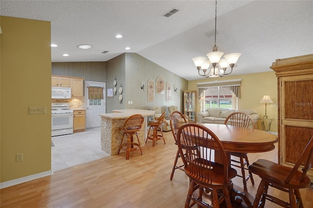 2766 Privada Dr, The Villages, FL 32162 - dining area with a chandelier, a textured ceiling, light wood finished floors, lofted ceiling, and baseboards