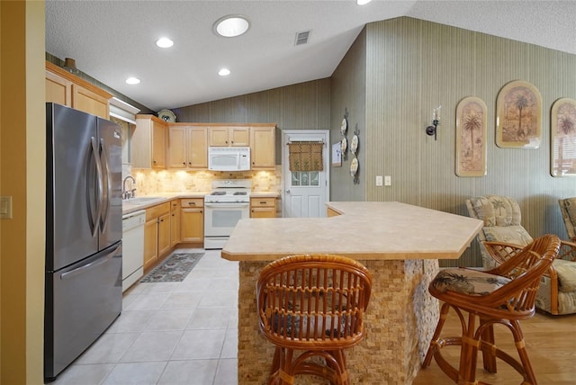 2766 Privada Dr, The Villages, FL 32162 - kitchen featuring white appliances, lofted ceiling, a sink, light brown cabinets, and a textured ceiling