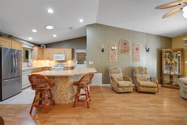 2766 Privada Dr, The Villages, FL 32162 - kitchen featuring white appliances, a sink, light brown cabinetry, light countertops, and lofted ceiling