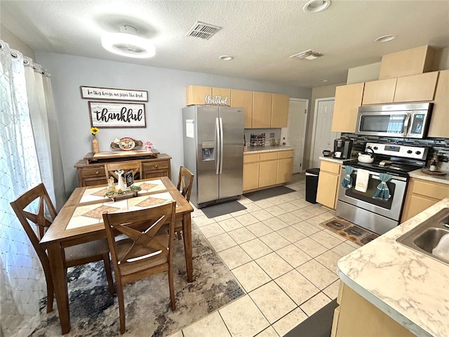 5051 NW 61st Ct, Ocala, FL 34482 - kitchen with stainless steel appliances, light brown cabinetry, light countertops, a textured ceiling, and light tile patterned floors