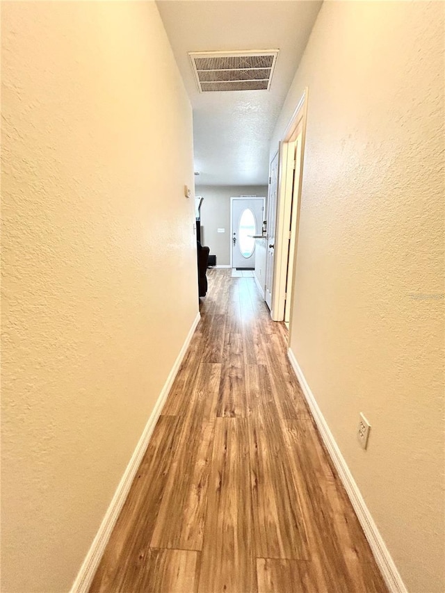 5051 NW 61st Ct, Ocala, FL 34482 - corridor featuring wood finished floors, a textured wall, and baseboards