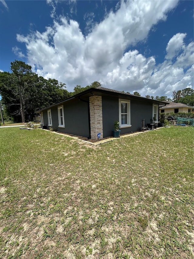 5051 NW 61st Ct, Ocala, FL 34482 - view of side of property featuring stucco siding, a lawn, and stone siding