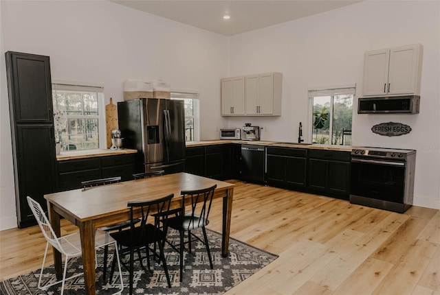 18142 Powerline Rd, Dade City, FL 33523 - kitchen featuring stainless steel appliances, a sink, light wood-type flooring, dark cabinetry, and recessed lighting