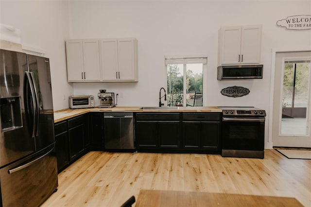 18142 Powerline Rd, Dade City, FL 33523 - kitchen featuring stainless steel appliances, a sink, white cabinets, and light wood finished floors