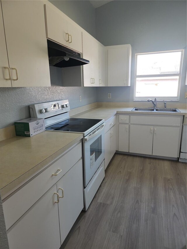 112 Arlington Ct, Haines City, FL 33844 - kitchen featuring electric range, under cabinet range hood, a sink, light countertops, and dark wood-style floors